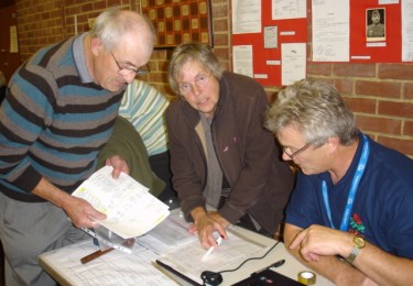 A group of 3 members looking over paper